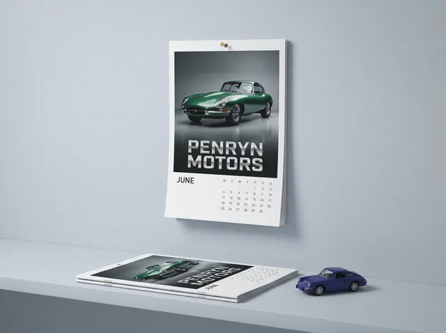 A Penryn Motors calendar hanging from a nail by its drilled hole, showing a green classic car