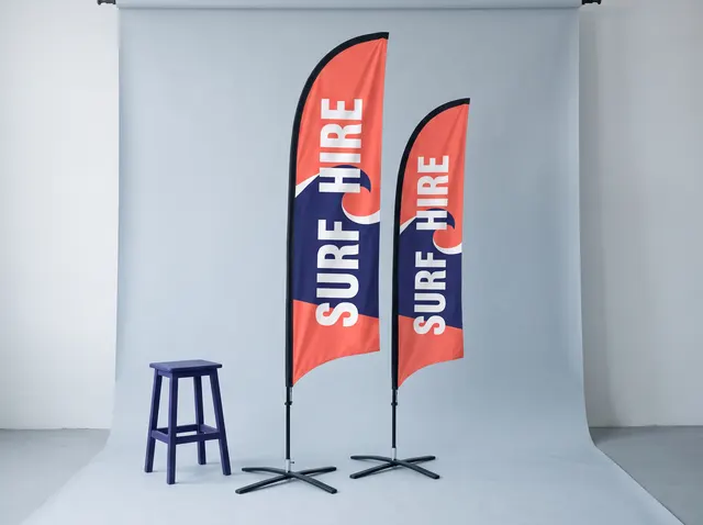 Two coral and navy Surf Hire feather flags on cross bases