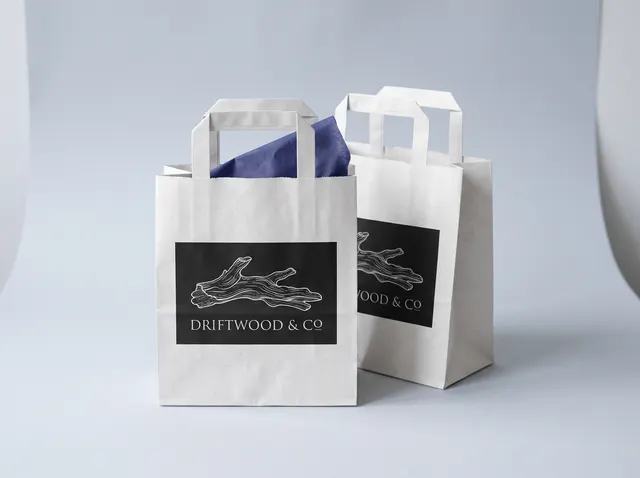 Brown kraft Driftwood & Co carrier bags with twisted handles and a black printed panel