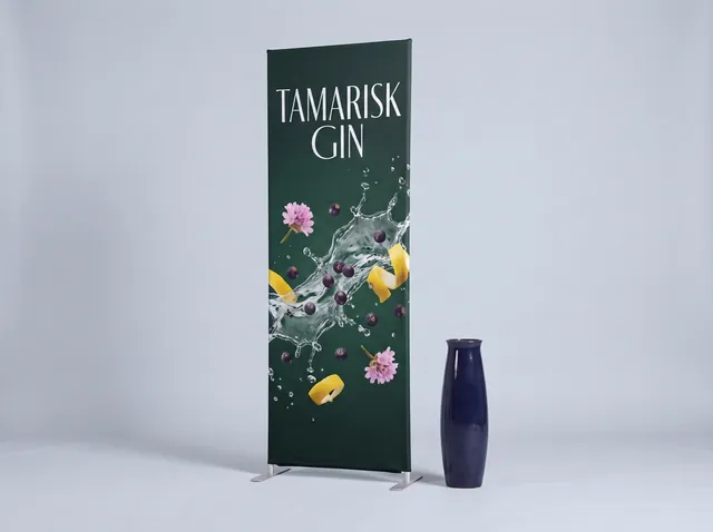 A green Tamarisk Gin fabric tube banner with a splash of gin and botanicals, on the standard frame with square corners and two feet