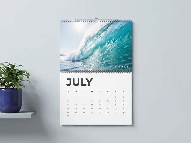 A Swell wall calendar showing a curling turquoise wave above July