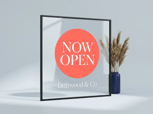 A Now Open window cling for Driftwood & Co on a pane of glass