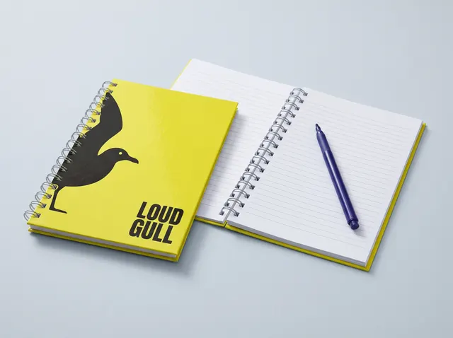 Yellow Loud Gull wire-bound notebooks, one open at lined pages