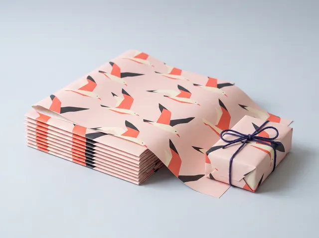 Folded sheets of blush wrapping paper with coral and black seagulls